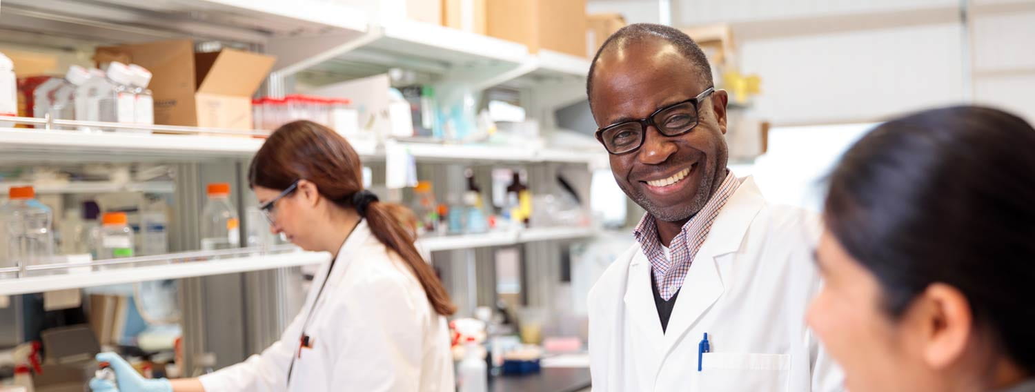 Gabriel Mbalaviele, PhD, works with members of his lab in the Institute of Health building.